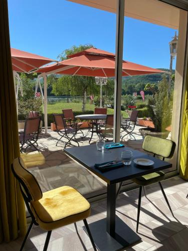 a patio with a table and chairs and an umbrella at Hôtel Restaurant du Lac in Boussens