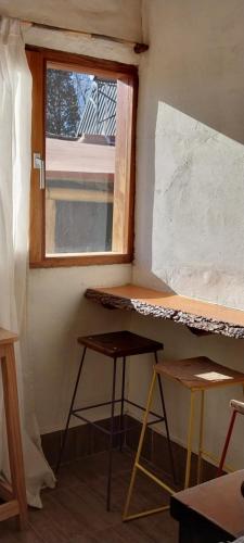 a room with a window and a desk and two stools at Cabañitas EL REPOSO HUMAHUACA in Humahuaca