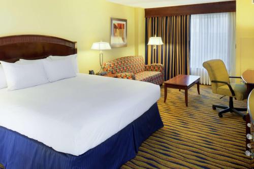 een hotelkamer met een groot bed en een stoel bij DoubleTree by Hilton Greensboro in Greensboro