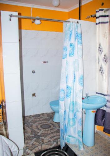 a bathroom with a blue toilet and a shower curtain at Secure Standalone 3BR Home near Embu Uni and KSG in Embu