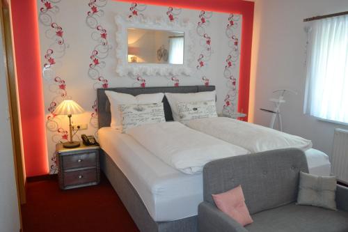 a bedroom with a bed with a mirror and a chair at Hotel & Restaurant Zur Linde in Freital