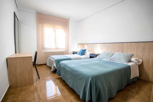 Un dormitorio con dos camas y un escritorio. en Casa Palau, en Morella