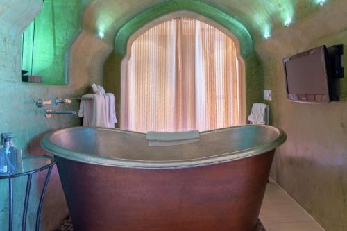 アルバカーキにあるHotel Andaluz Albuquerque, Curio Collection By Hiltonの窓付きのバスルーム(大きな木製バスタブ付)