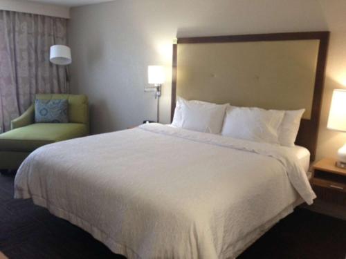 Hampton Inn Tampa-Rocky Point في تامبا: غرفة فندقية بسرير كبير وكرسي