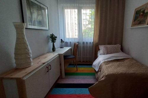 um quarto com uma cama, uma secretária e uma janela em Zielona Wiolinowa em Varsóvia