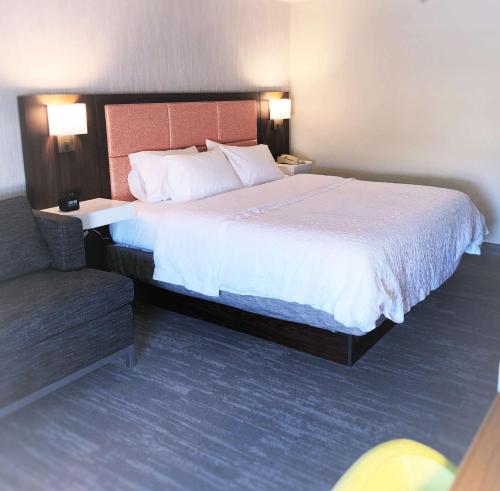 a hotel room with a large bed and a chair at Hampton Inn Williamsport in Williamsport