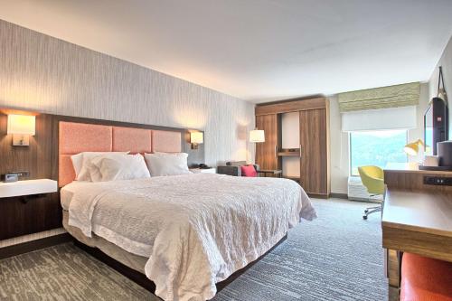 a hotel room with a large bed and a desk at Hampton Inn Williamsport in Williamsport