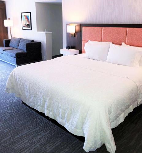 a hotel room with a large white bed and a couch at Hampton Inn Williamsport in Williamsport