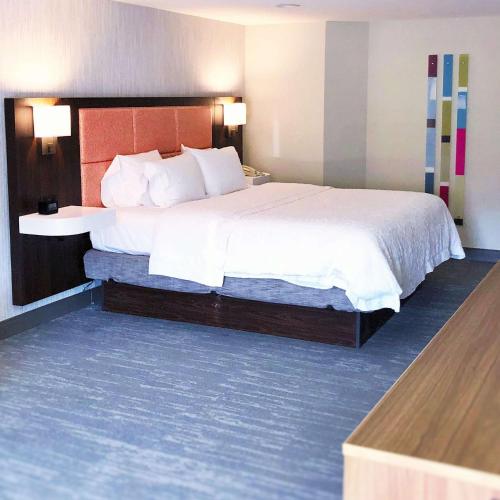 a hotel room with a large bed with white sheets at Hampton Inn Williamsport in Williamsport