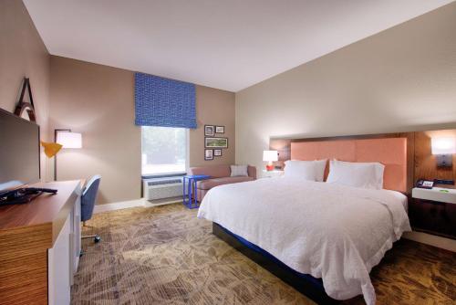 Habitación de hotel con cama grande y escritorio. en Hampton Inn Baton Rouge - Denham Springs, en Denham Springs