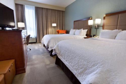 a hotel room with two beds and a flat screen tv at Hampton Inn St. Louis Southwest in Fenton