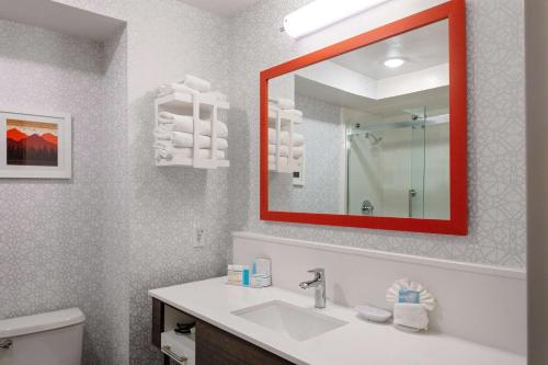 Hampton Inn Castle Rock في كاسل روك: حمام مع حوض ومرآة حمراء