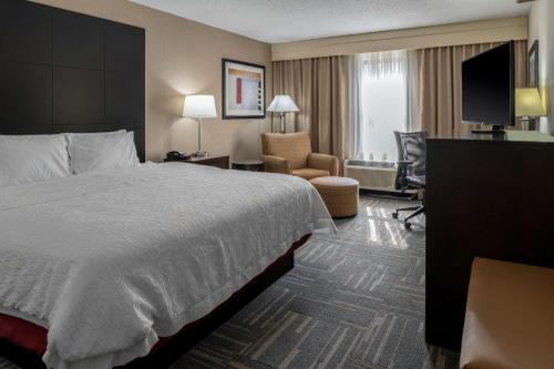 a hotel room with a large bed and a chair at Hampton Inn Columbia in Columbia