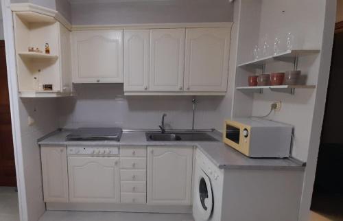 una cucina con mobili bianchi, un lavello e un microonde di LA CASITA SERRANA a Puerto de Béjar
