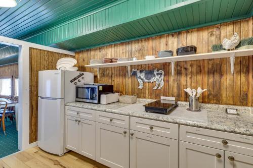 a kitchen with a white refrigerator and wooden walls at Charming Converted Railcar Studio in Joplin! in Joplin