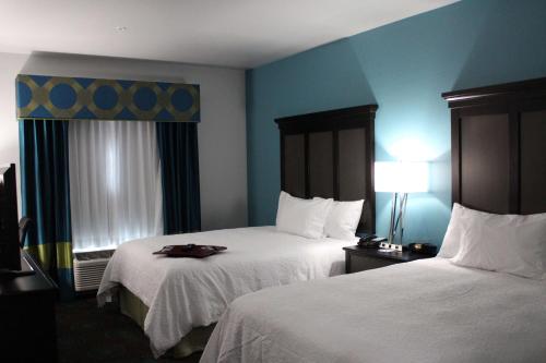 a hotel room with two beds and a lamp at Hampton Inn Cotulla in Cotulla