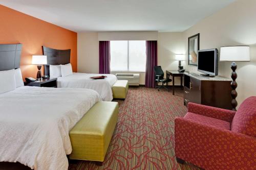 ein Hotelzimmer mit 2 Betten und einem Stuhl in der Unterkunft Hampton Inn Seneca Falls in Seneca Falls