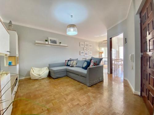 a living room with a blue couch and a wooden floor at Quarteira Beach Apartment by Homing in Quarteira