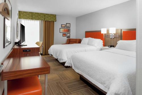 a hotel room with two beds and a desk and a television at Hampton Inn Miami/Dadeland in South Miami