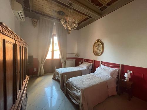 a bedroom with two beds and a chandelier and a window at Appartamento Sant'Ambrogio in Florence