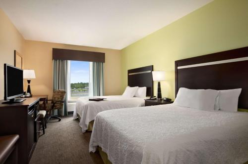 a hotel room with two beds and a television at Hampton Inn Belton/Kansas City in Belton