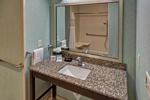 La salle de bains est pourvue d'un lavabo et d'un grand miroir. dans l'établissement Hampton Inn Belton/Kansas City, à Belton