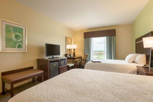 a hotel room with two beds and a flat screen tv at Hampton Inn Belton/Kansas City in Belton
