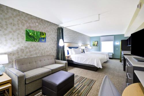 モーミーにあるHome2 Suites By Hilton Maumee Toledoのベッドとソファ付きのホテルルーム