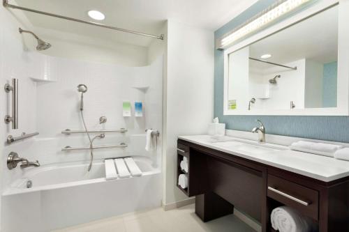 a bathroom with a tub and a sink and a mirror at Home2 Suites by Hilton Middletown in Middletown