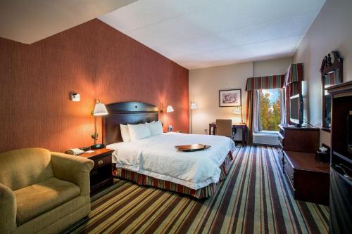 Hampton Inn Sturbridge في ستيربريدج: غرفه فندقيه بسرير وكرسي