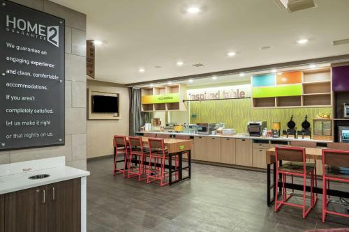 a restaurant with red chairs and a kitchen with a counter at Home2 Suites By Hilton Dayton Centerville in Centerville