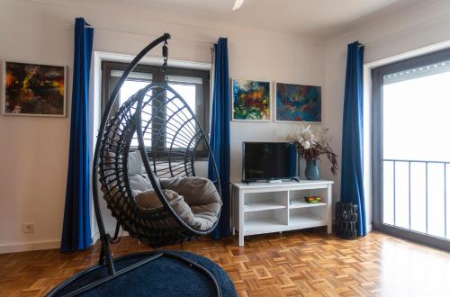エリセイラにあるSea Ceiling - Ericeiraのハンギングチェアとテレビ付きの客室です。