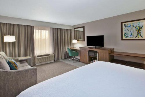 a hotel room with a bed and a desk with a television at Hampton Inn & Suites Alliance in Alliance