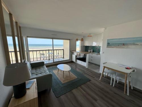 un salon avec un canapé et une table et une cuisine dans l'établissement Vue mer exceptionnelle à Cabourg, à Cabourg