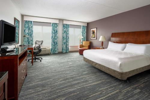 a hotel room with a bed and a flat screen tv at Hilton Garden Inn Mystic/Groton in Groton