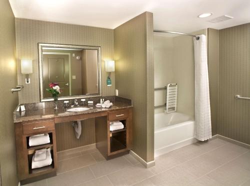a bathroom with a sink and a tub and a mirror at Homewood Suites by Hilton Newport-Middletown in Middletown