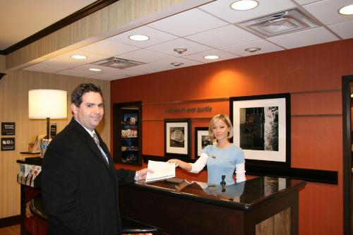 un hombre y una mujer parados en una caja registradora en Hampton Inn & Suites New Castle, PA, en New Castle