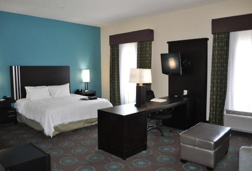 a hotel room with a bed and a desk and a television at Hampton Inn Pleasanton in Pleasanton