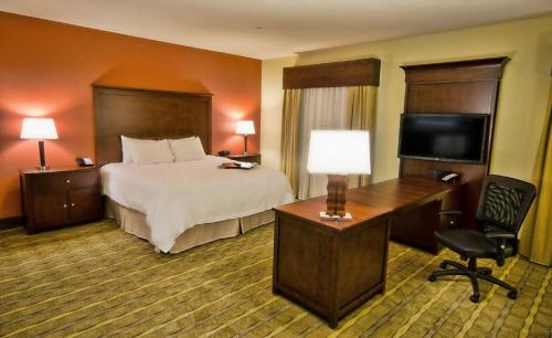 a hotel room with a bed and a desk and a television at Hampton Inn & Suites Tifton in Tifton
