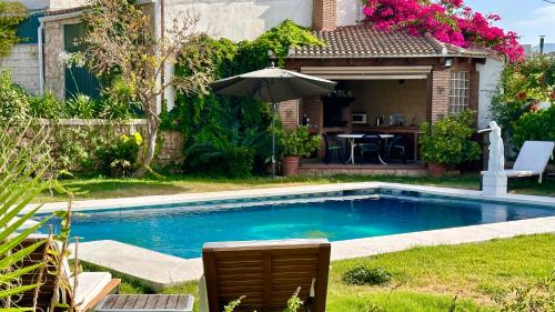 een zwembad in een tuin met een parasol bij Villa Huerta del Sur - Piscina privada y barbacoa in Alhaurín el Grande