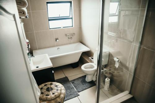 a bathroom with a tub and a toilet and a sink at Sizakele Stays in Johannesburg
