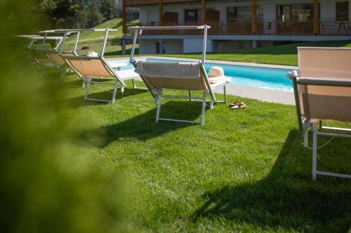 a row of chairs sitting in the grass next to a pool at Natur Residence Kaiser Hans in Schenna