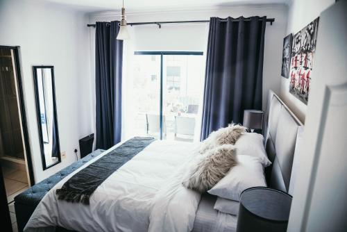 a bedroom with a bed with white sheets and a window at Sizakele Stays in Johannesburg
