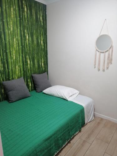 セトゥーバルにあるCasa da Avó Alice by Casas de Setubalの緑のカーテンが備わるドミトリールームのベッド1台分です。