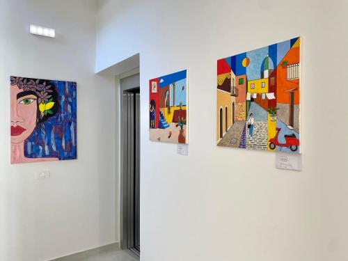 a group of paintings hanging on a wall in a room at Hotel Arte Mare in San Vito lo Capo