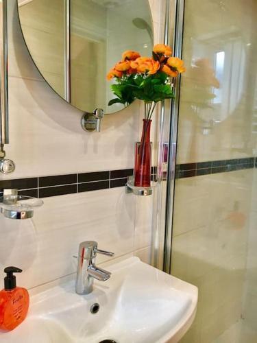 a bathroom with a sink and a vase with orange flowers at One Bedroom Flat in Central London in London