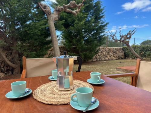 Sa Caseta d'Artrutx في كالا إن بوش: وعاء القهوة على طاولة مع أكواب وصحون