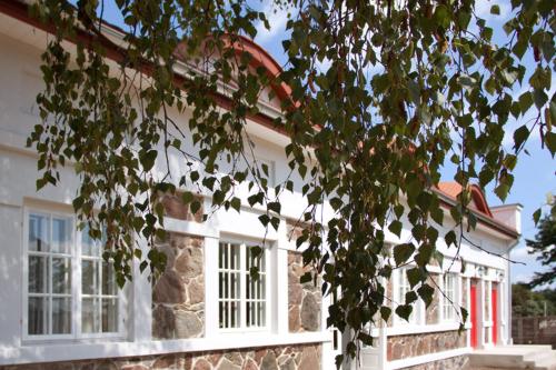 a white house with white windows and a tree at Kuźnia Pałacowa in Korczew