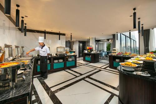 a chef standing in a kitchen in a restaurant at MAY DE VILLE Lakeside Hotel in Hanoi