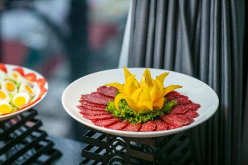 a plate of food with fruit on a table at MAY DE VILLE Lakeside Hotel in Hanoi